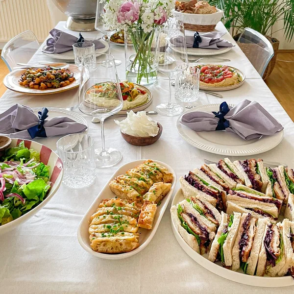 A long brunch table set with sandwiches, salads and flowers